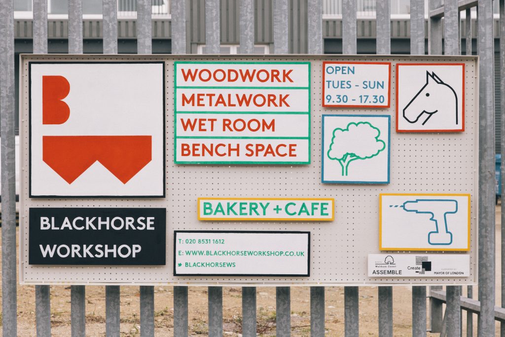Signs on a metal fence that provide information about opening times and the Blackhorse Workshop