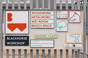 Signs on a metal fence that provide information about opening times and the Blackhorse Workshop