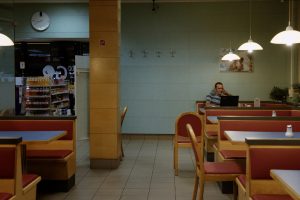 Innenaufnahme von einem Gasthaus mit einer Person mit Laptop