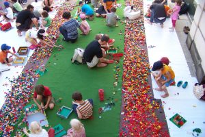 Lots of people erecting buildings using a huge amount of Lego bricks