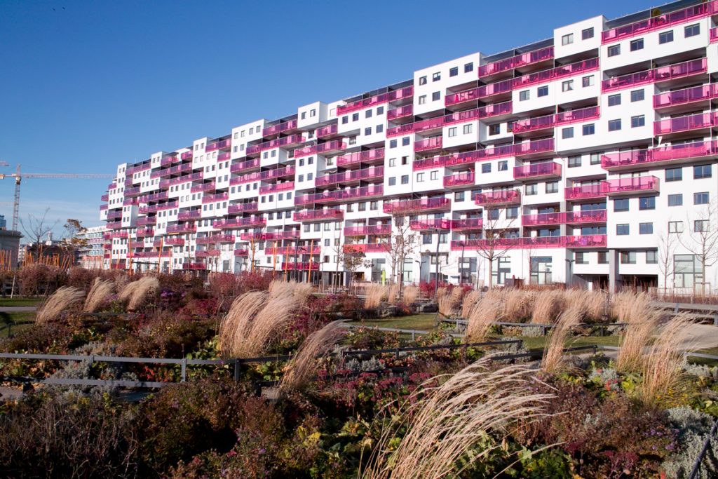 An elongated housing block with pink-coloured balcony parapets