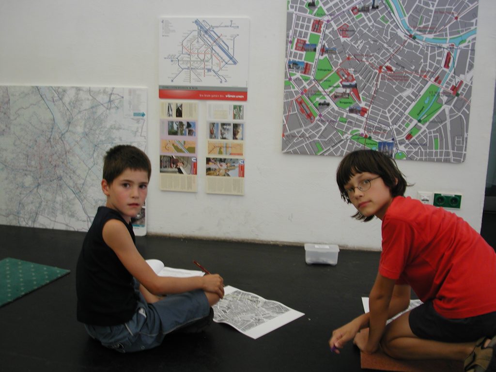 Zwei Kinder betrachten bei einem Workshop verschiedene Wienpläne