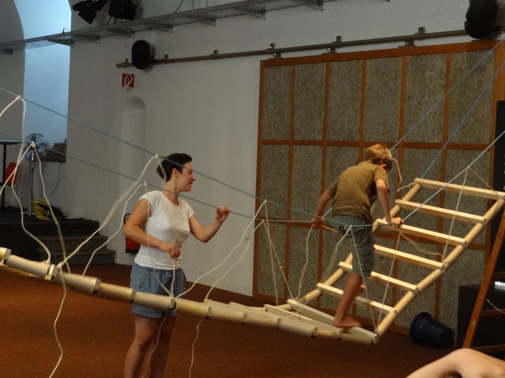 Ein Kind geht über eine selbstgebaute Hängebrücke