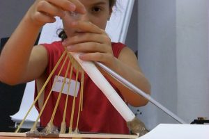 A child working on the model of a bridge.