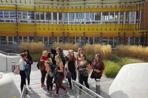 Group of school students in front of a yellow and orange striped building.