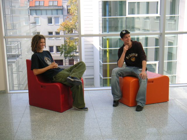 Two young people sitting on chairs they have built themselves.