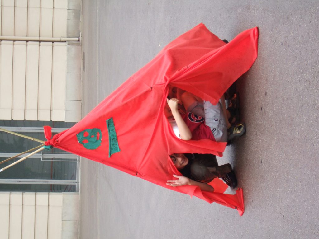 Children in a red tent they have built themselves