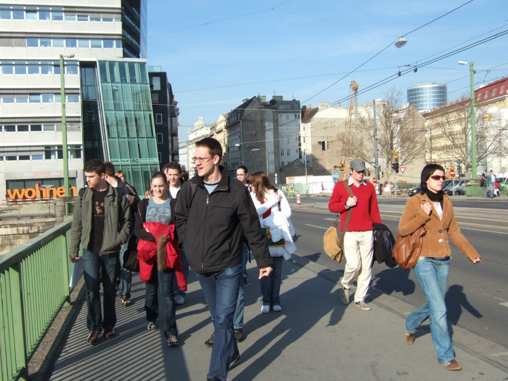 Schüler*innengruppe geht über den Donaukanal, im Hintergrund ist ein Bürotower zu sehen