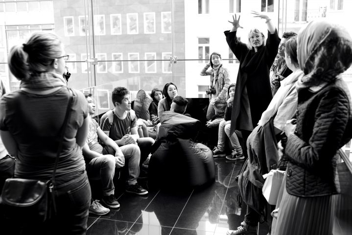 An amused group watches the video installation of an artist in a hotel