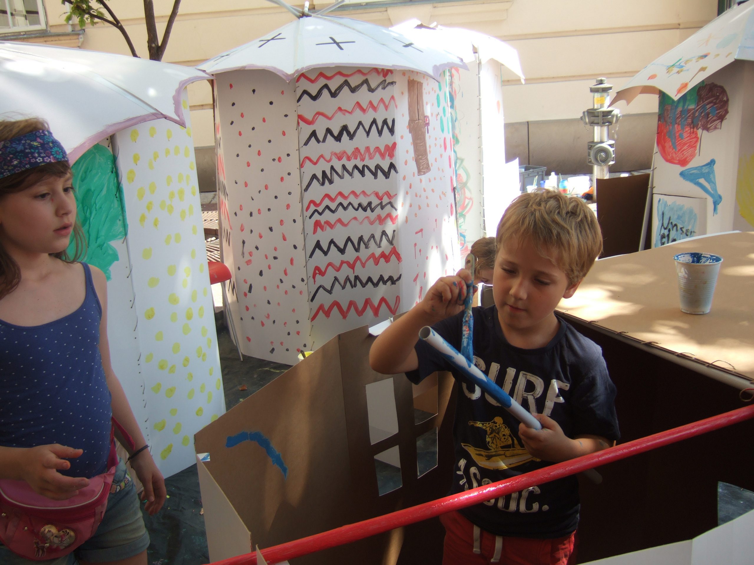 Children paint their cardboard house