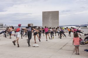 Menschen, die in einem Kreis stehen, ein Bein und die beide Arme anheben