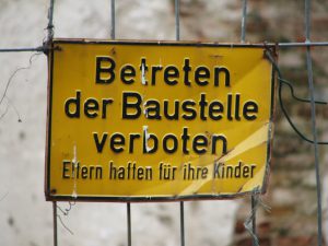Warnhinweisschild mit dem Schriftzug „Betreten der Baustelle verboten. Eltern haften für ihre Kinder“