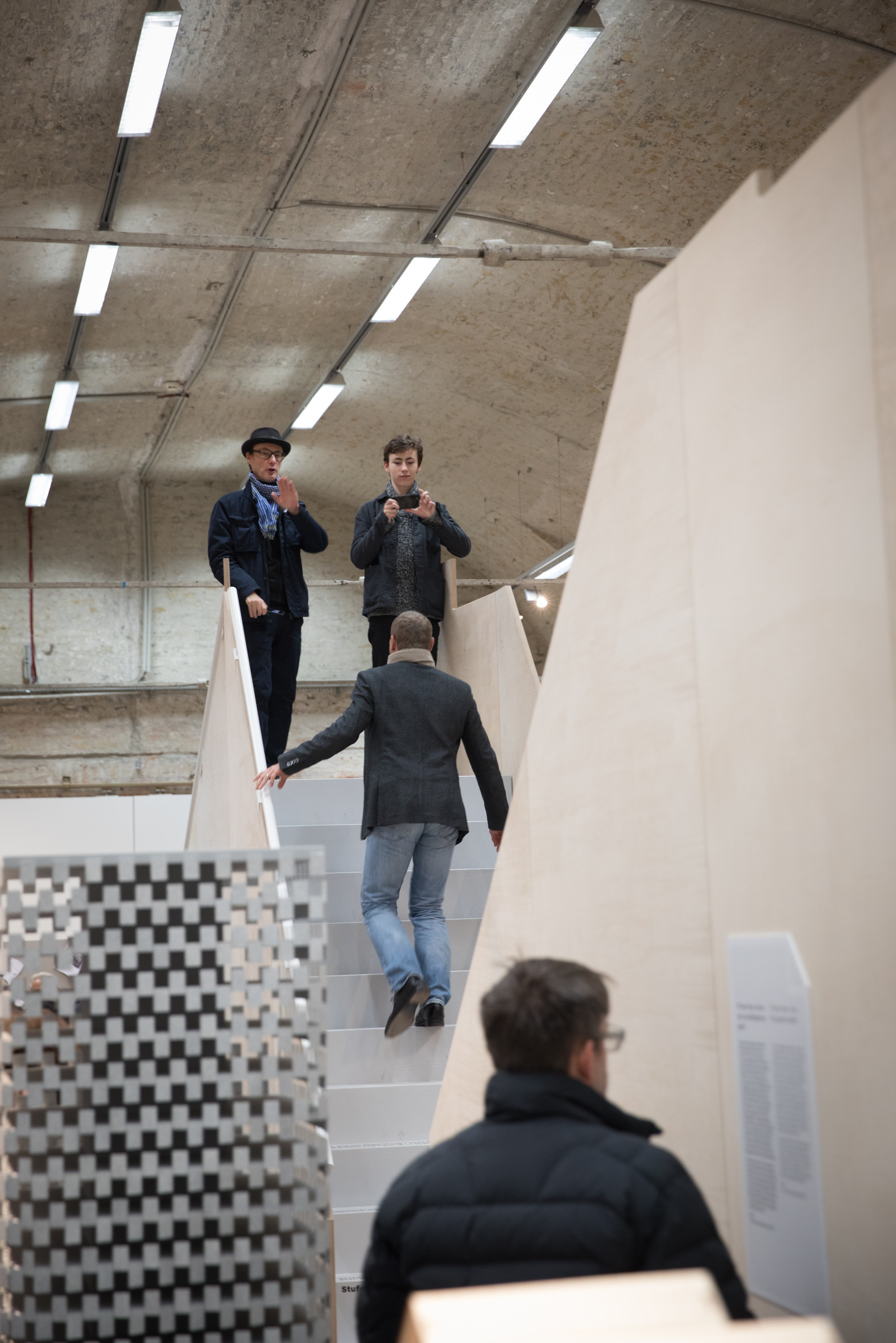 3 Männer auf einer Treppe, einer davon geht hinauf