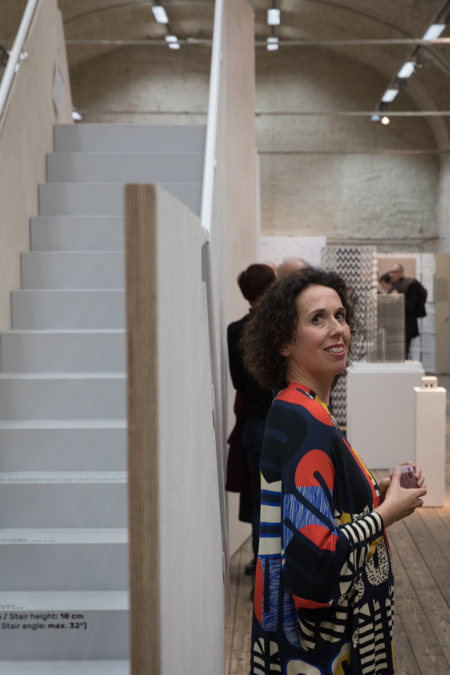 Dunkelhaarige Frau mit bunten Kleid vor einer Treppe