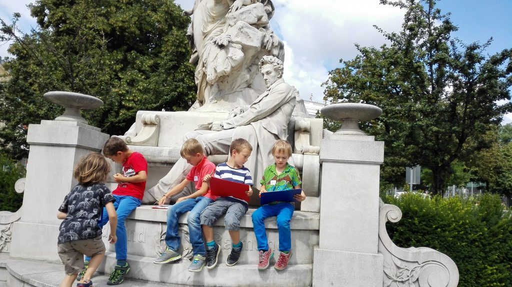 Kinder sitzen auf einem Monument