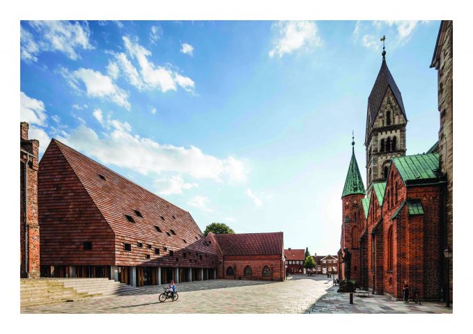paved square with gabled roof building on the left and church on the right
