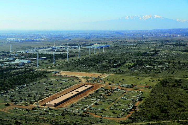 Aerial view of the area with rectangular museum building in the foreground, surrounded by green areas; wind turbines in the background