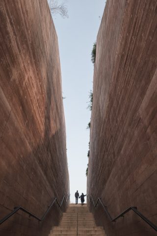 View of a staircase leading up to the upper end. There are two people. To the left and right of the stairs rise gorge-like walls