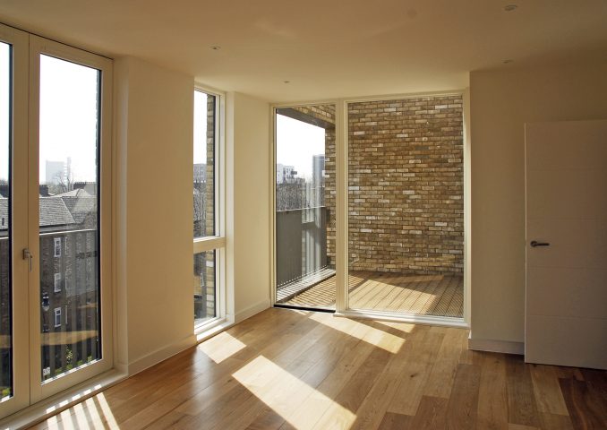 Interior view with view from large rectangular windows, which extend from the ceiling to the floor, onto the exterior and stone wall