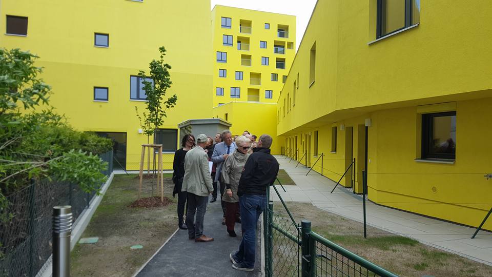 A group of people in front of a yellow apartment block.