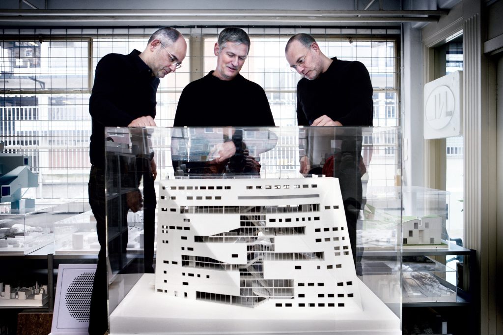 Three man standing around an architectural model