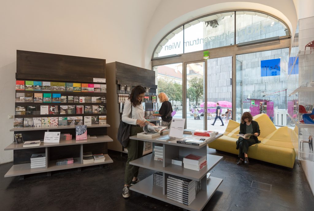 Innenansicht einen Raumes mit Bücherregal , Büchertisch und Sofa und drei lesenden Frauen