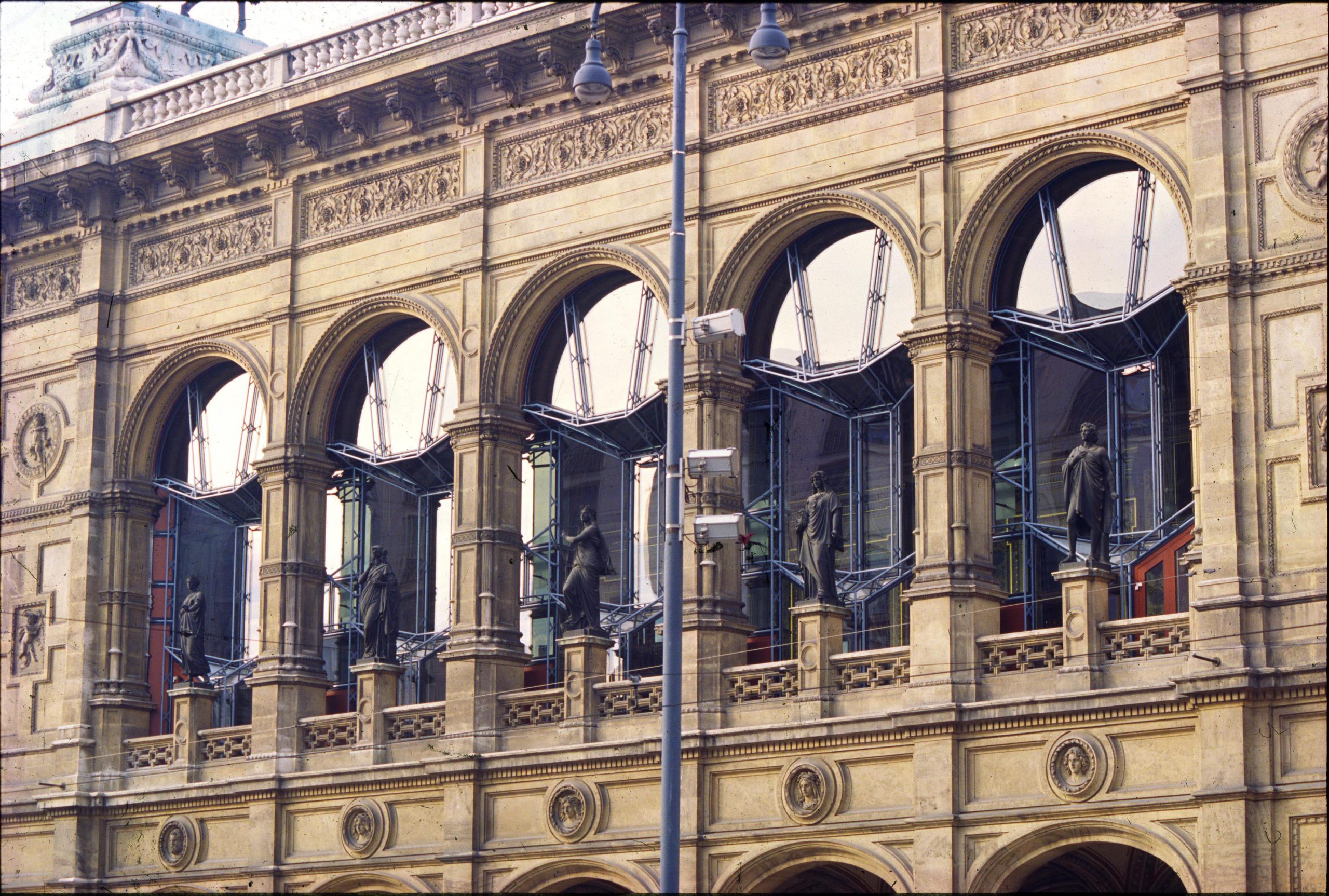 Facade of buidling with large, semicircular windows and sculptures in front of the windows