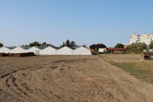 weiße flache Lagerhallen mit einem Acker im Vordergrund