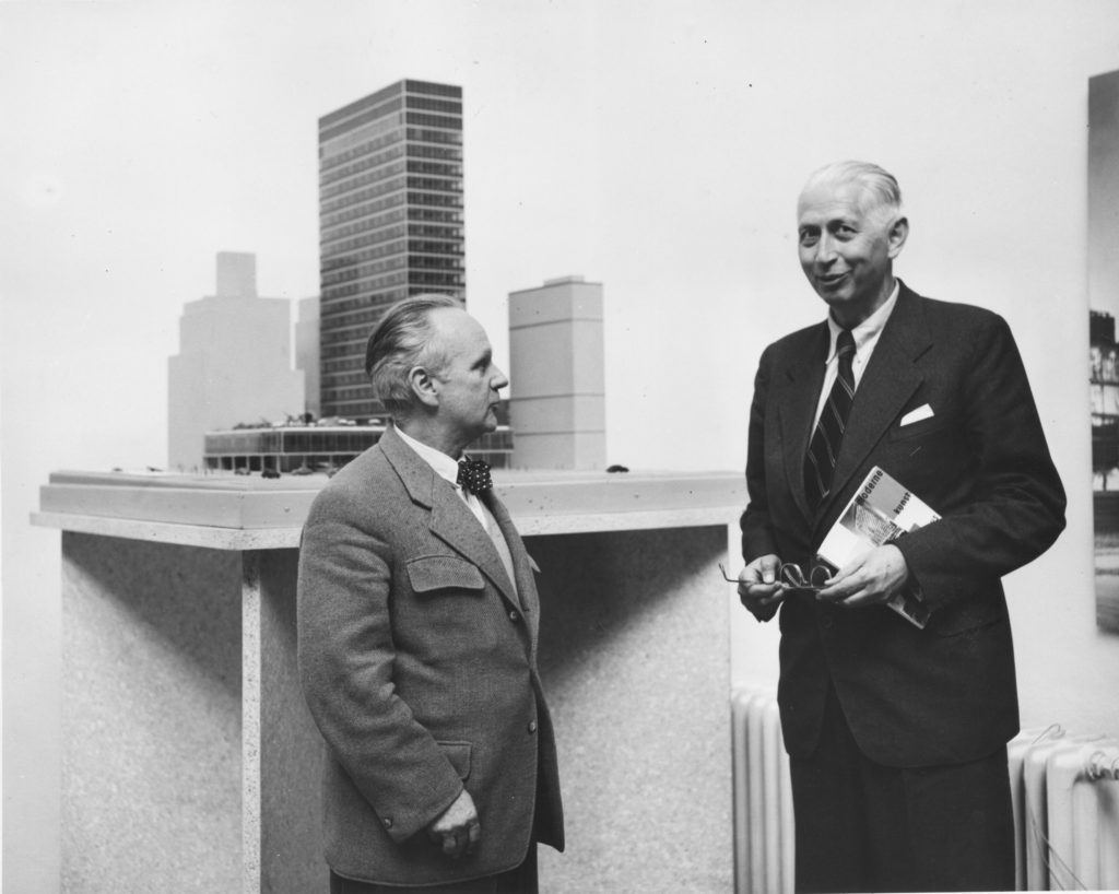 Black and white photo of two elderly men in a suit in front of an architectural model