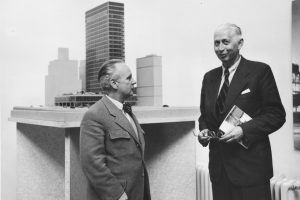 Black and white photo of two elderly men in a suit in front of an architectural model