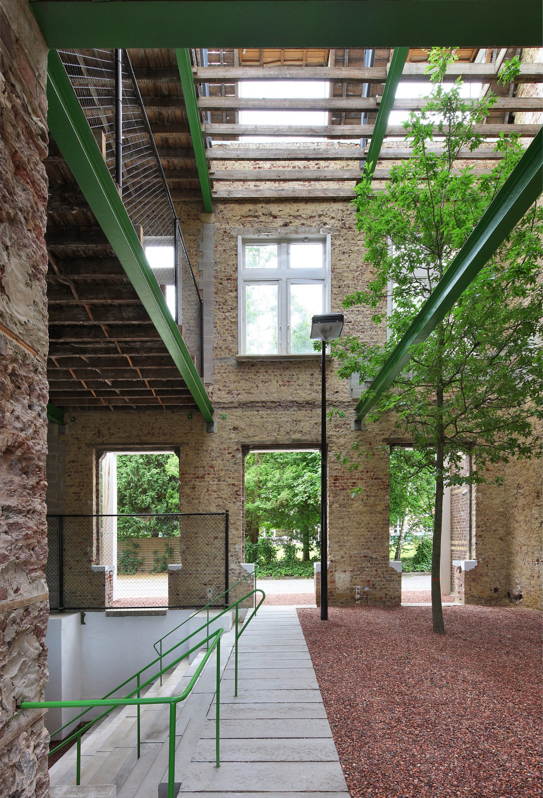 Innenansicht eines ausgehöhlten Gebäudes mit Balkonen, Treppe und einem Baum