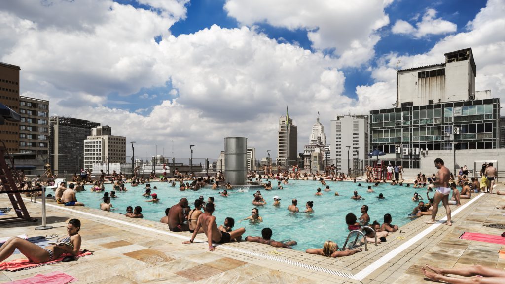 Swimming pool on a roof with bathing people and skyscrapers in the background