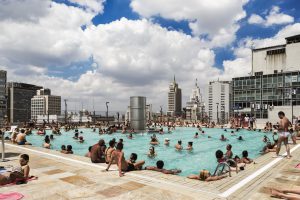 Swimming pool on a roof with bathing people and skyscrapers in the background