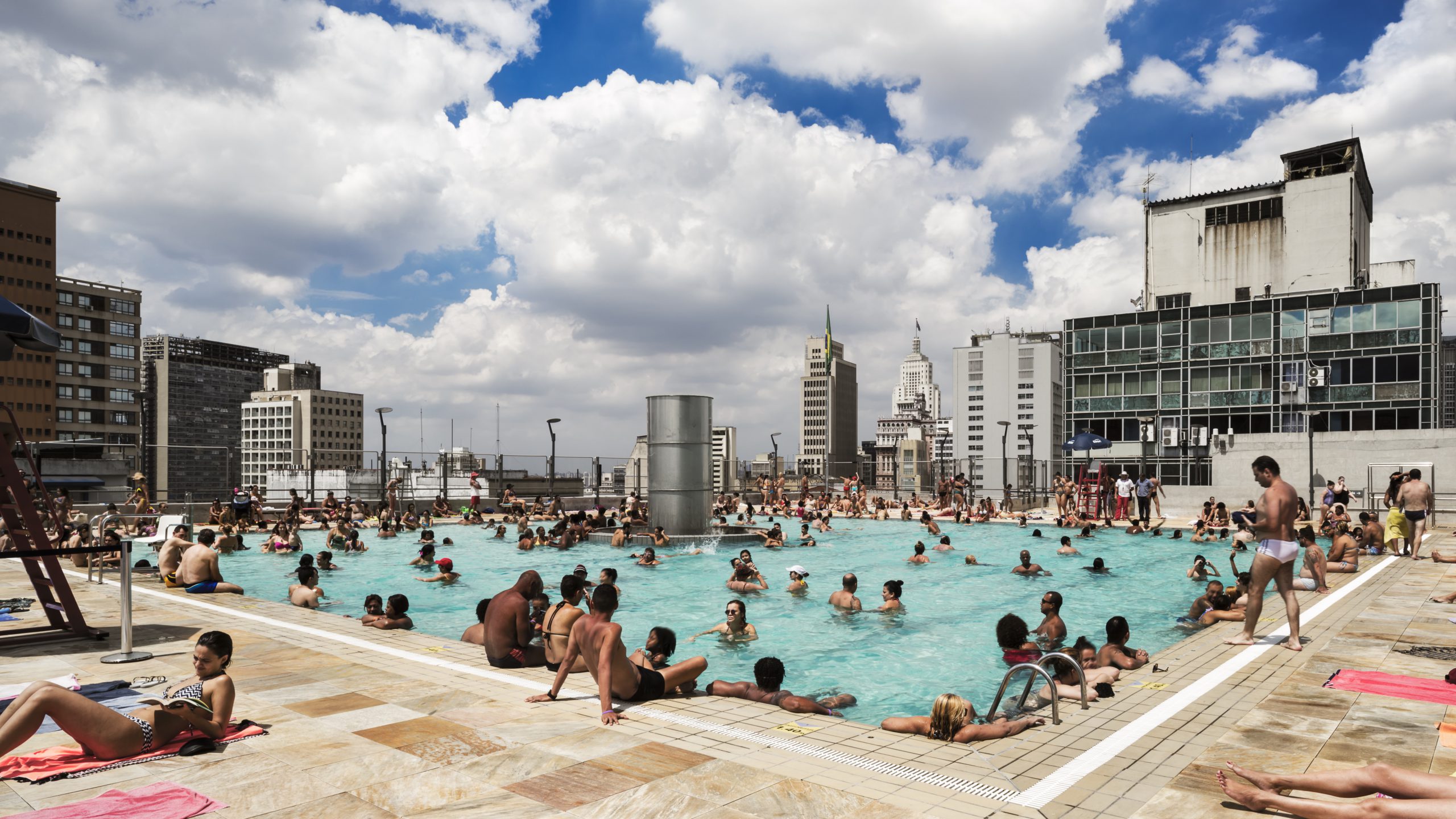 Swimmingpool auf eine Dach mit badenden Menschen und Hochhäusern im Hintergrund