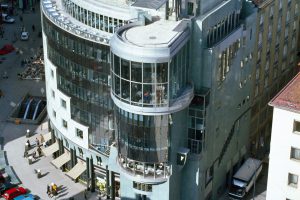 Multi-storey semicircular building with glass facade and parking cars in front of it