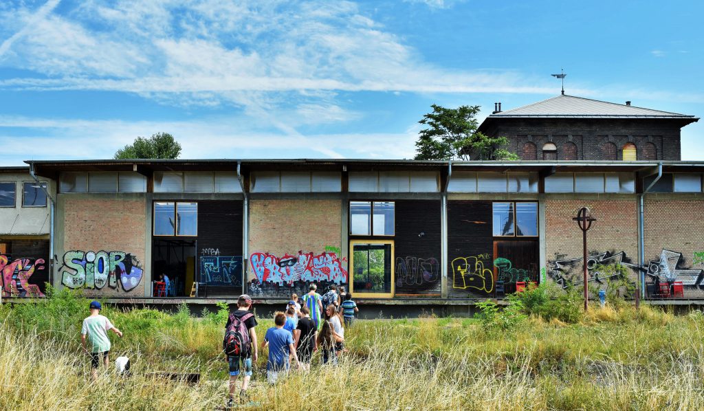 Group of people walking through a meadow towards a flat building