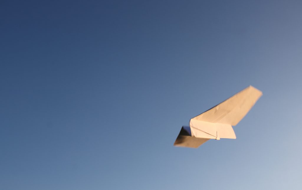 Papierflieger und blauer Himmel