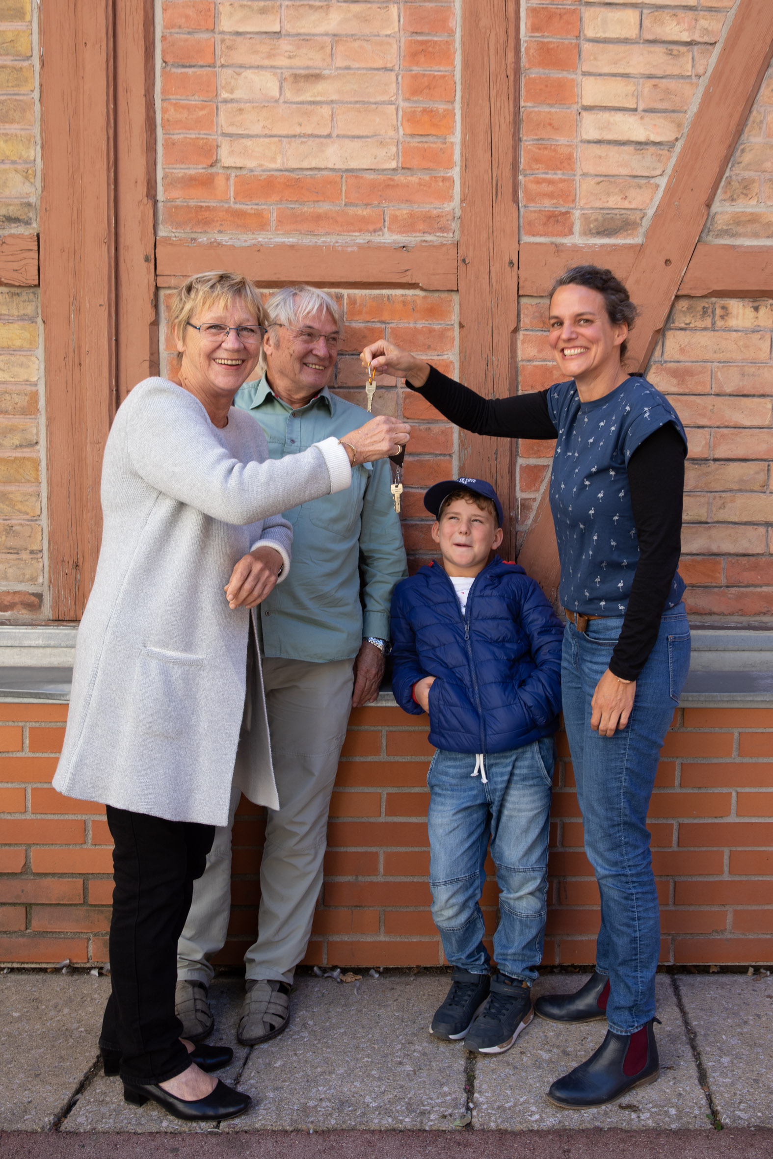 3 Personen mit Kind vor Ziegelwand