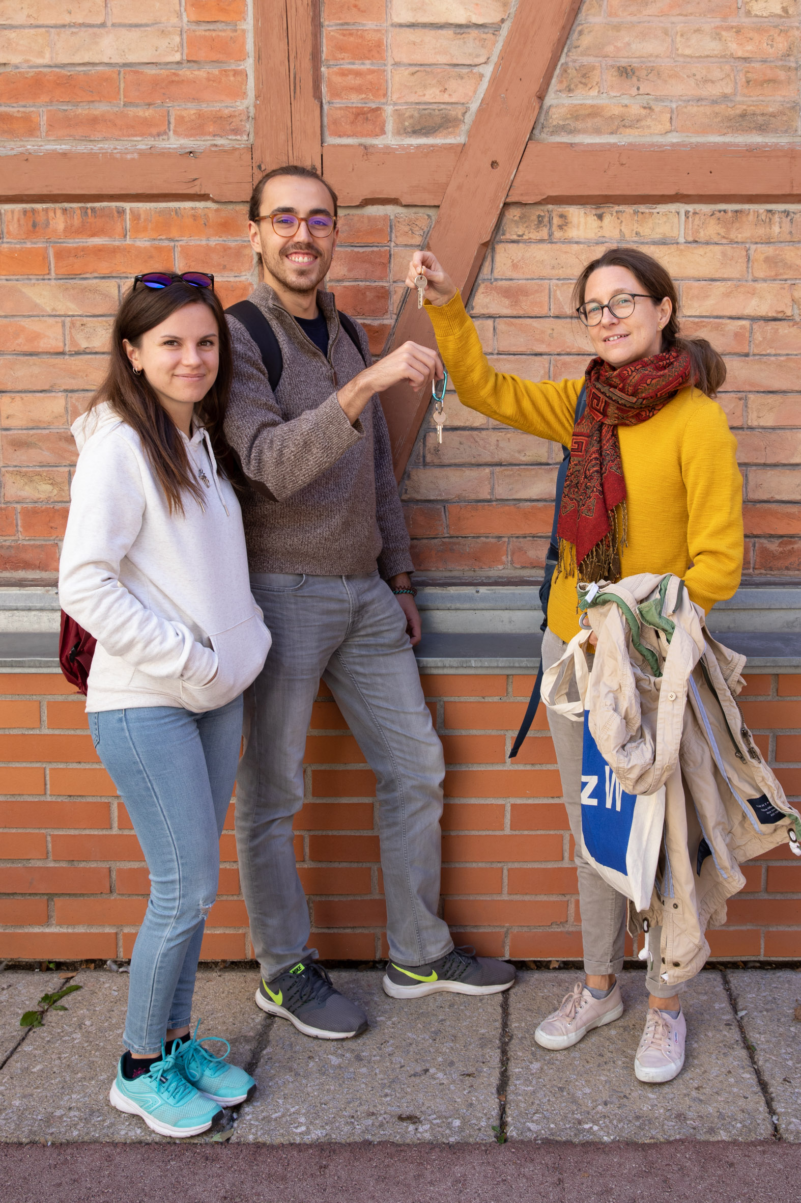 3 Personen vor Ziegelwand