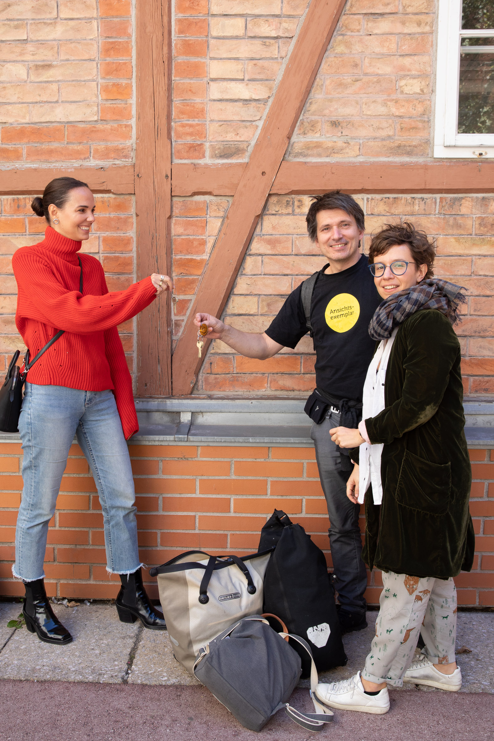 3 Personen vor Ziegelwand