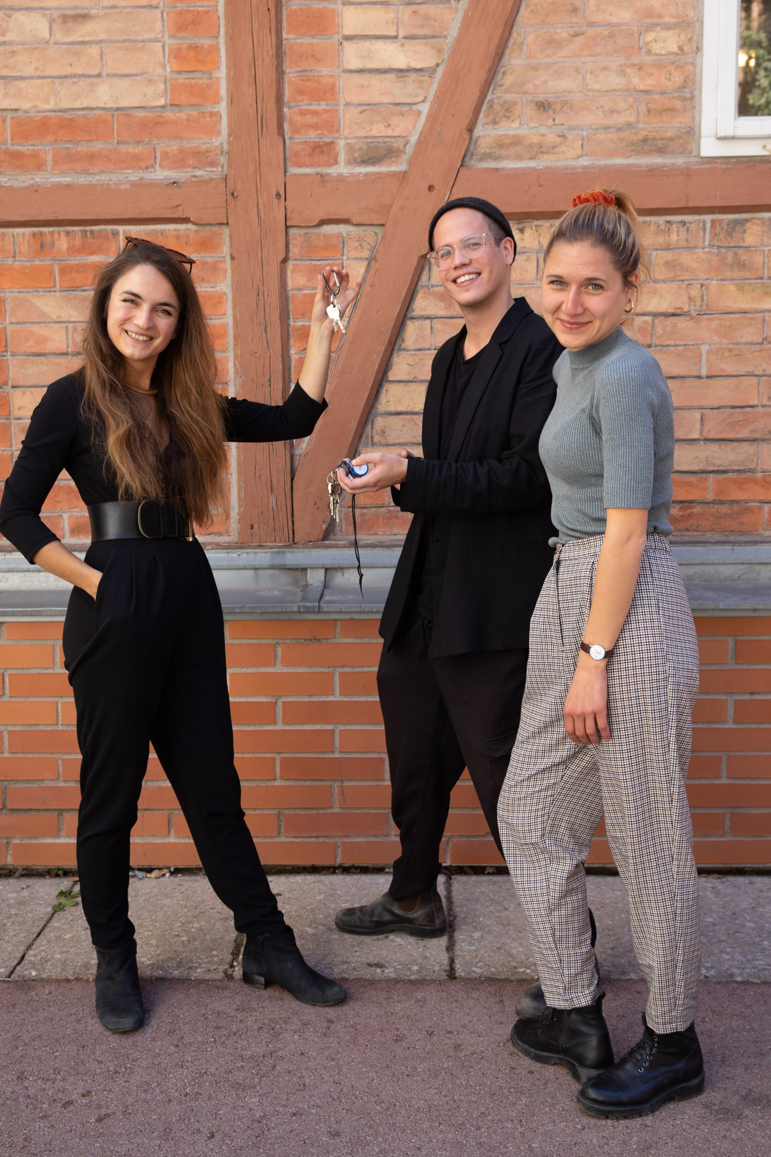 3 Personen vor Ziegelwand