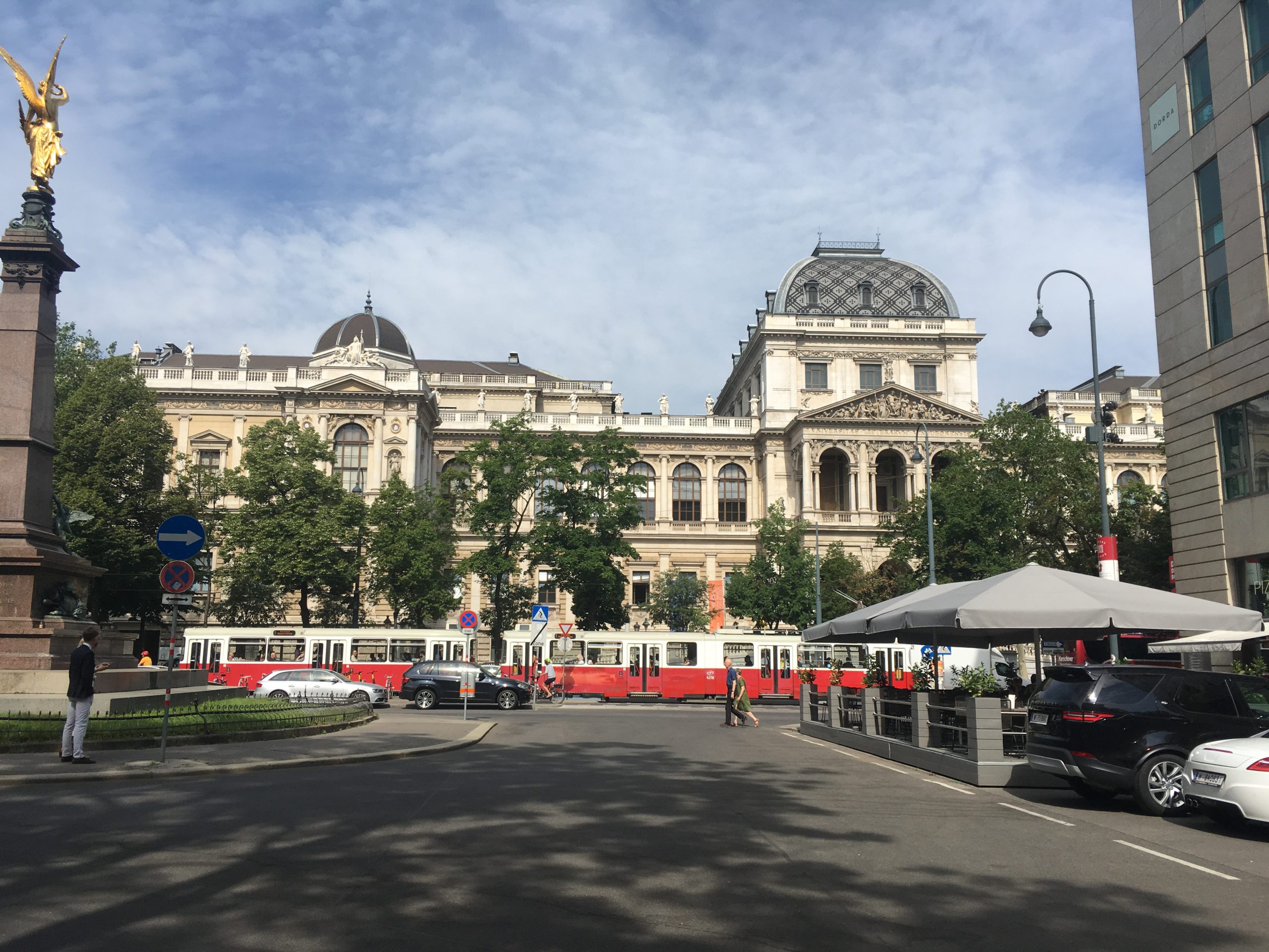 A red tram in front of a large building