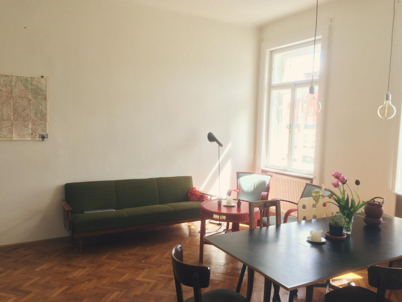 Living room with a green couch and tables with chairs