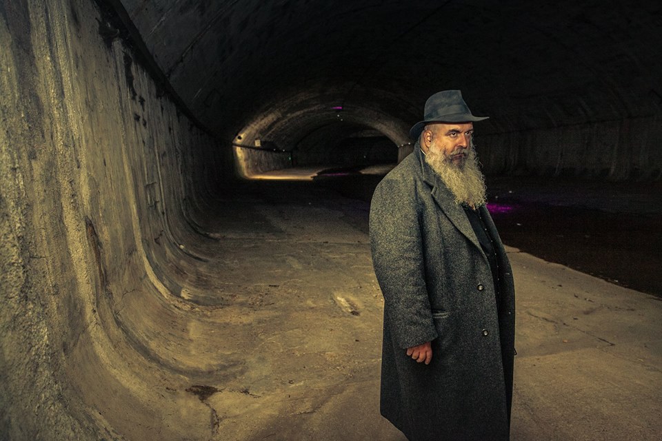 a man with a long grey beard and hat in a canal shaft