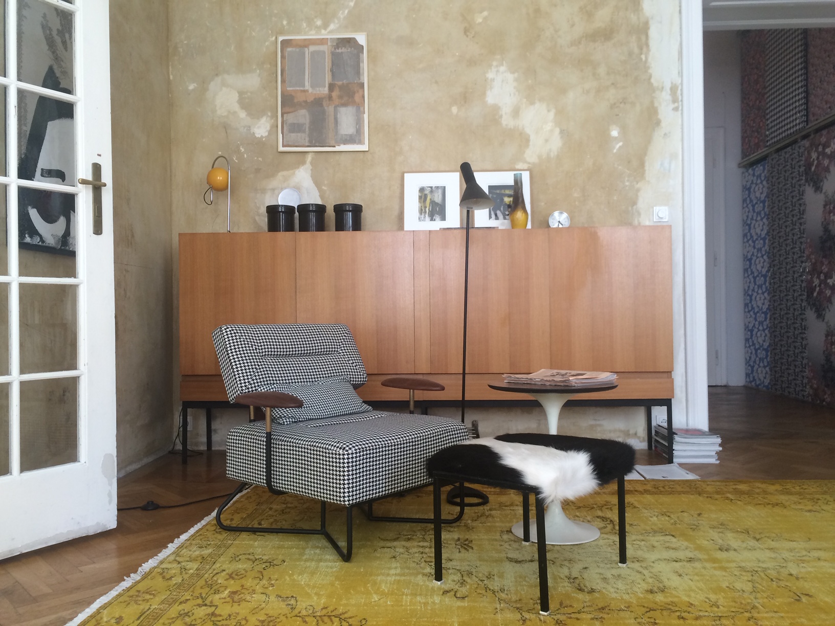 brown sideboard, armchair with checkered cover and stool with fur cover.