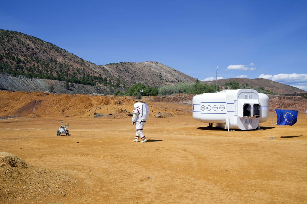 man dressed in white, a small vehicle and a white object in desert area
