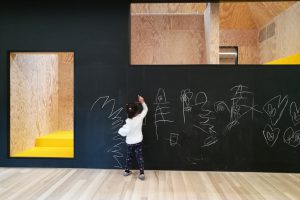 Kind bemalt schwarze Wand, die eine Tür- und eine Fensteröffnung aufweist
