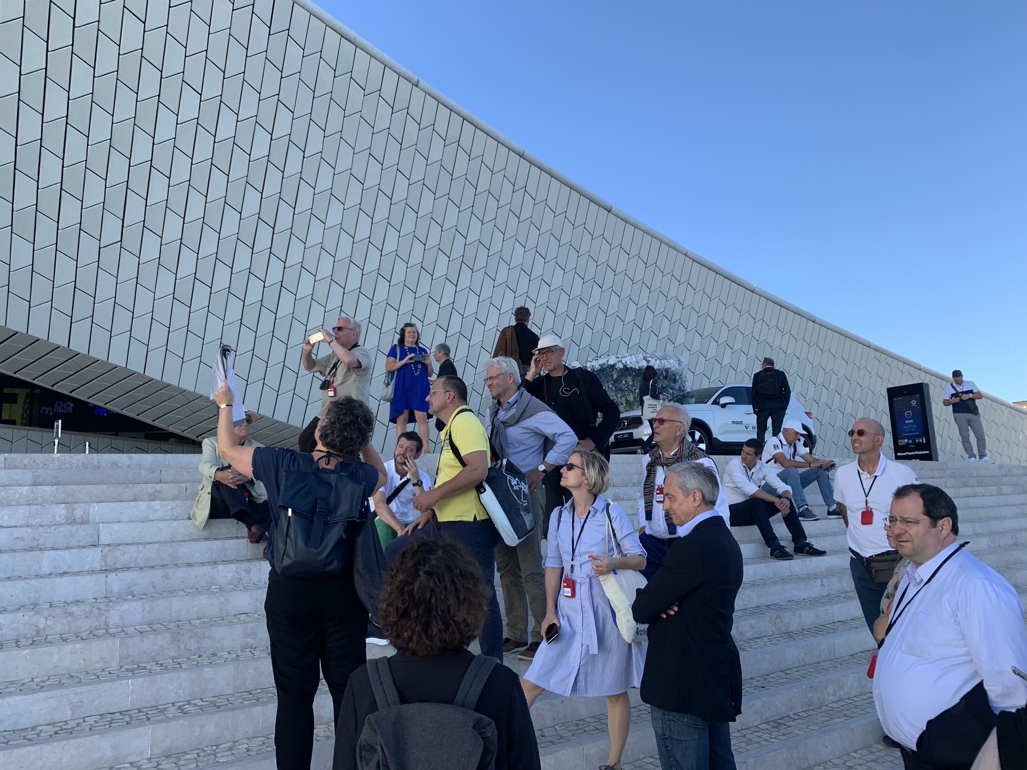 Group of people in front of y white facade, blue sky