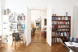 Mann in weißer Hose in Wohnung mit vielen Büchern