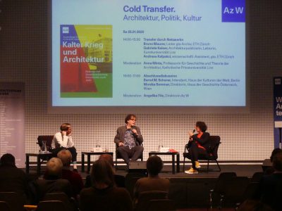 3 Personen in dunklem Raum vor großer Leinwand mit Titel "Kalter Krieg und Architektur"